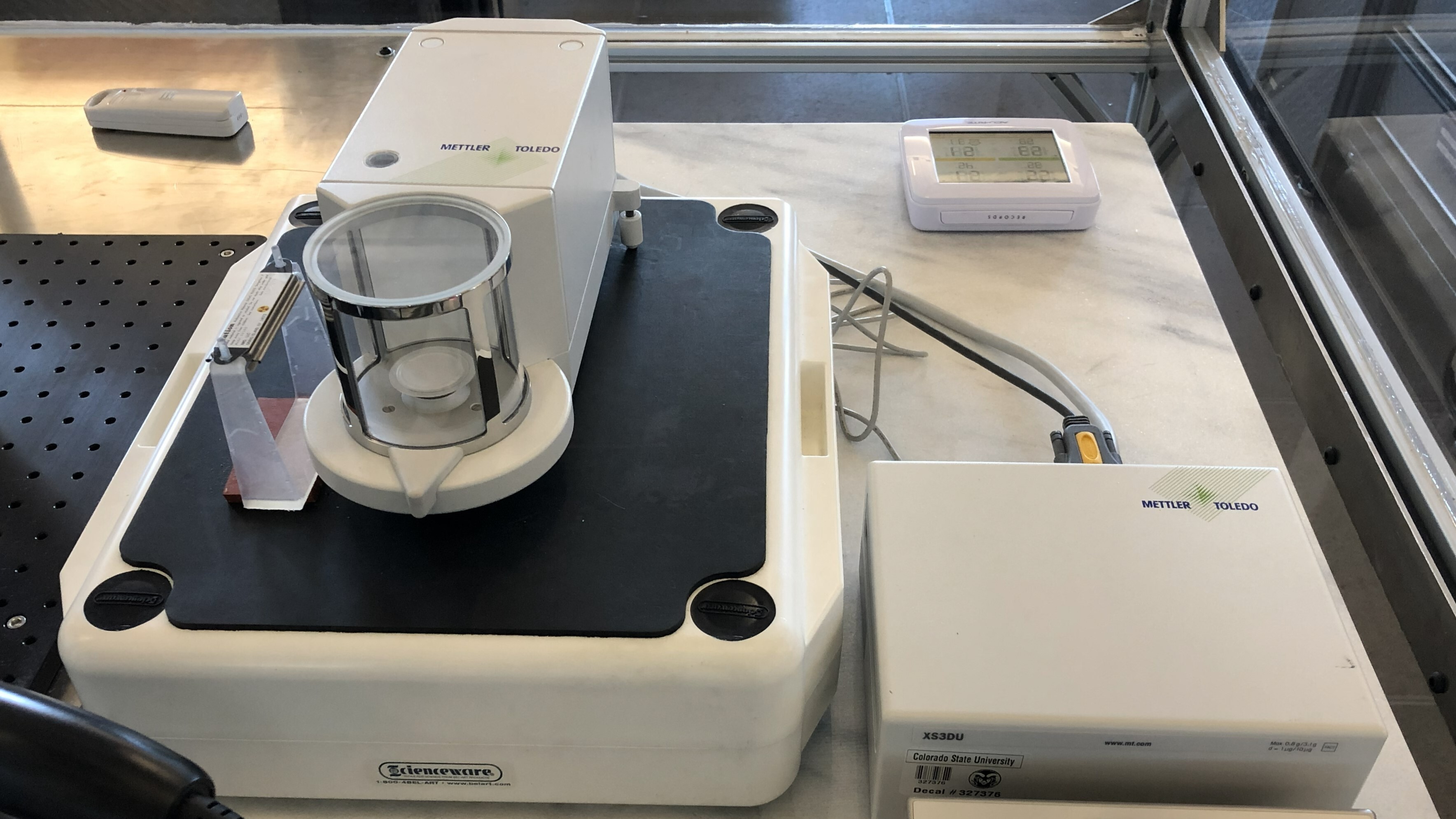 A photograph of a particulate matter sampling filter being weighed on a microbalance.